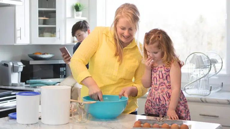 Mother and daughter baking with boy on phone