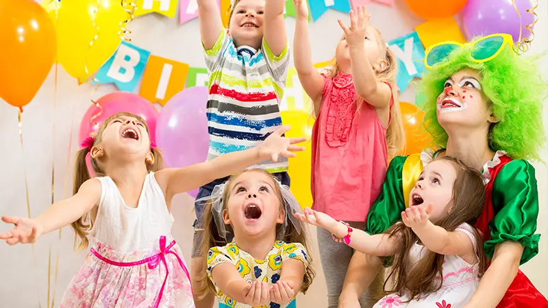 Kids enjoying a birthday party with balloons and clown