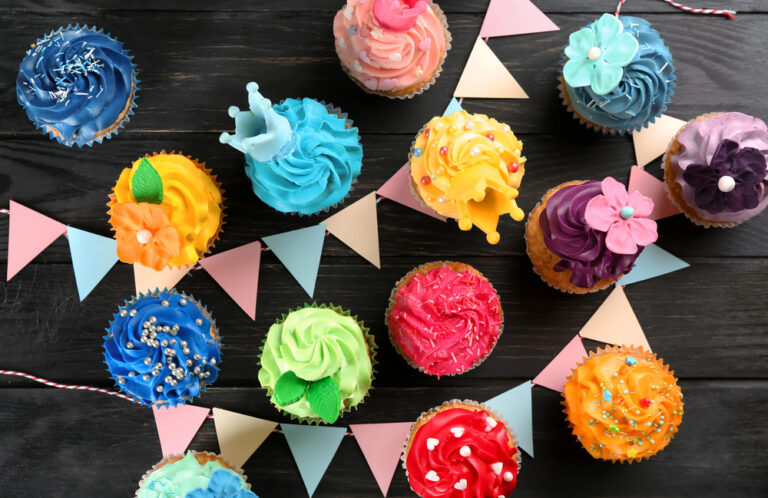 Tasty cupcakes and party decor on dark wooden background