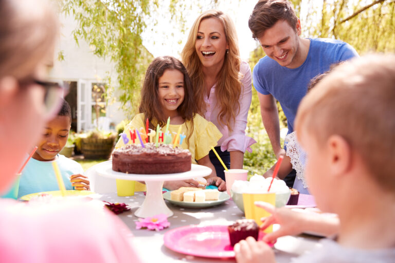 Parents And Daughter Celebrating Birthday With Friends Having Party In Garden At Home