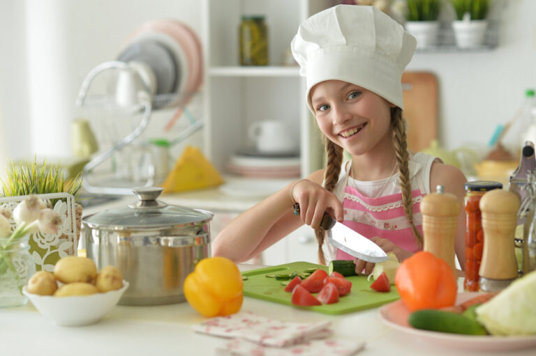 Cute happy girl coocking on kitche