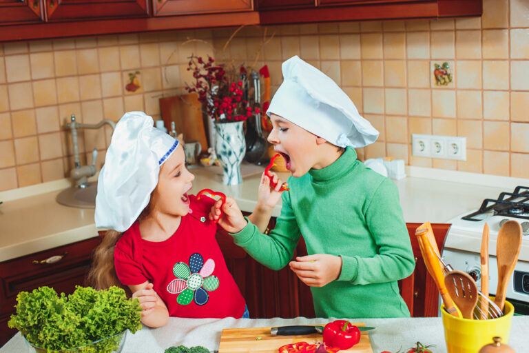 happy family funny kids are preparing the a fresh vegetable salad in the kitchen