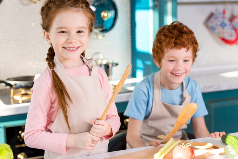 Adorable kids in aprons laughing while cooking