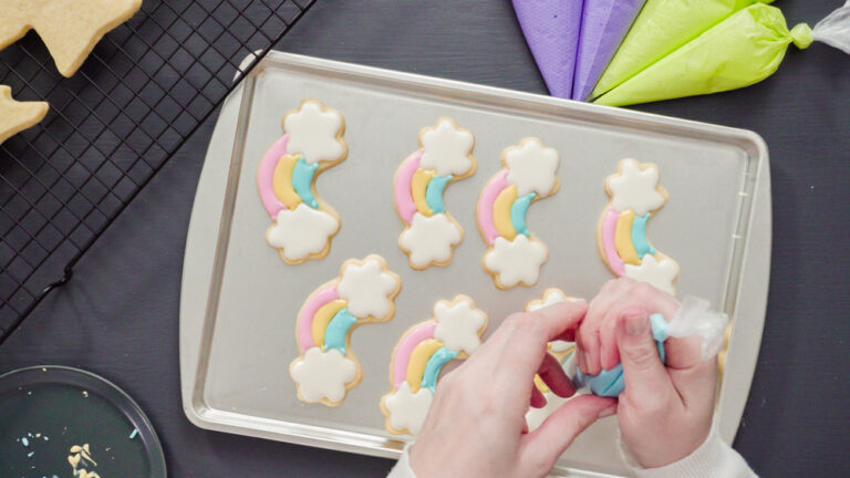 Flat lay. Decorating unicorn sugar cookies with multi-color royal icing.