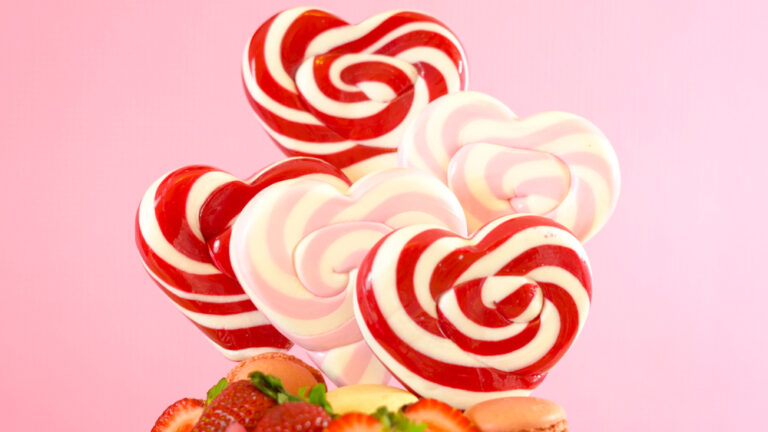 Candyland fantasy drip novelty cake decorated with heart shaped lollipops, candy and fresh strawberries.