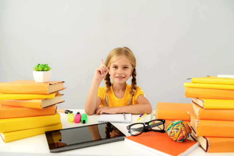 Intelligent child sitting at the desk with books