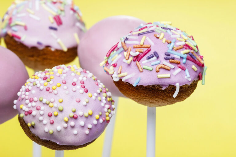 Pink cake pops on yellow background.