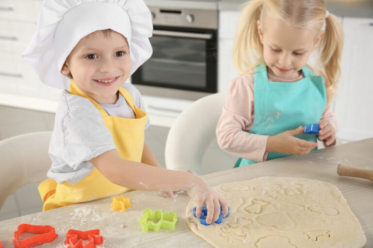 Little kids making biscuits on table