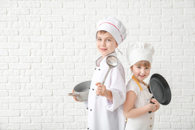 Cute little chefs with utensils on white brick background