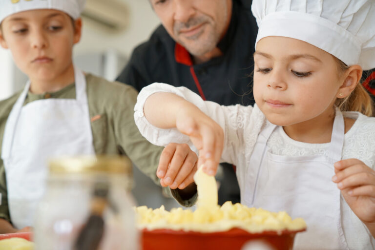 Pastry chef watching kids preparing apple pie