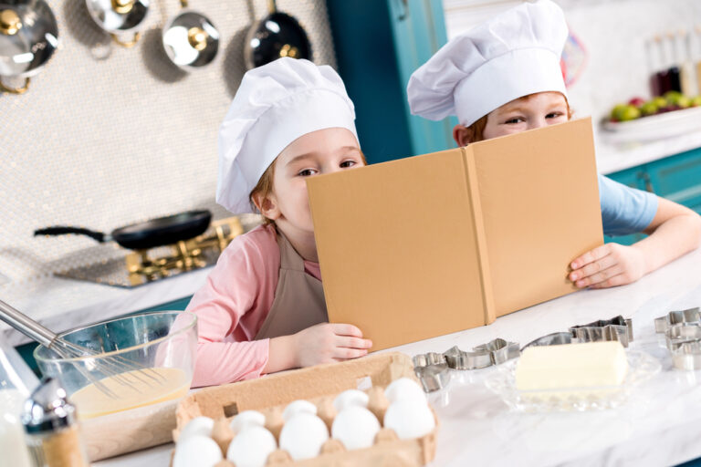 Adorable children in chef hats holding cookbook