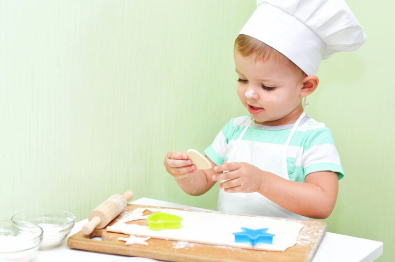 A little baker in a white suit chef bakes cookies